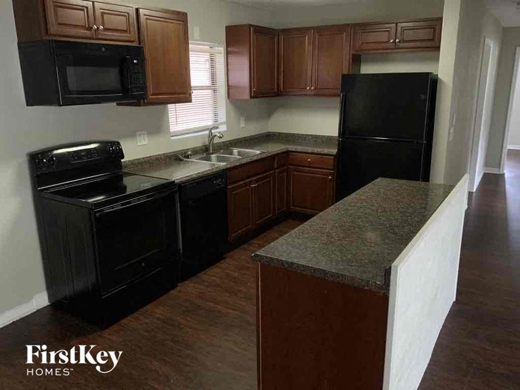 an empty kitchen with black appliances and brown cabinets