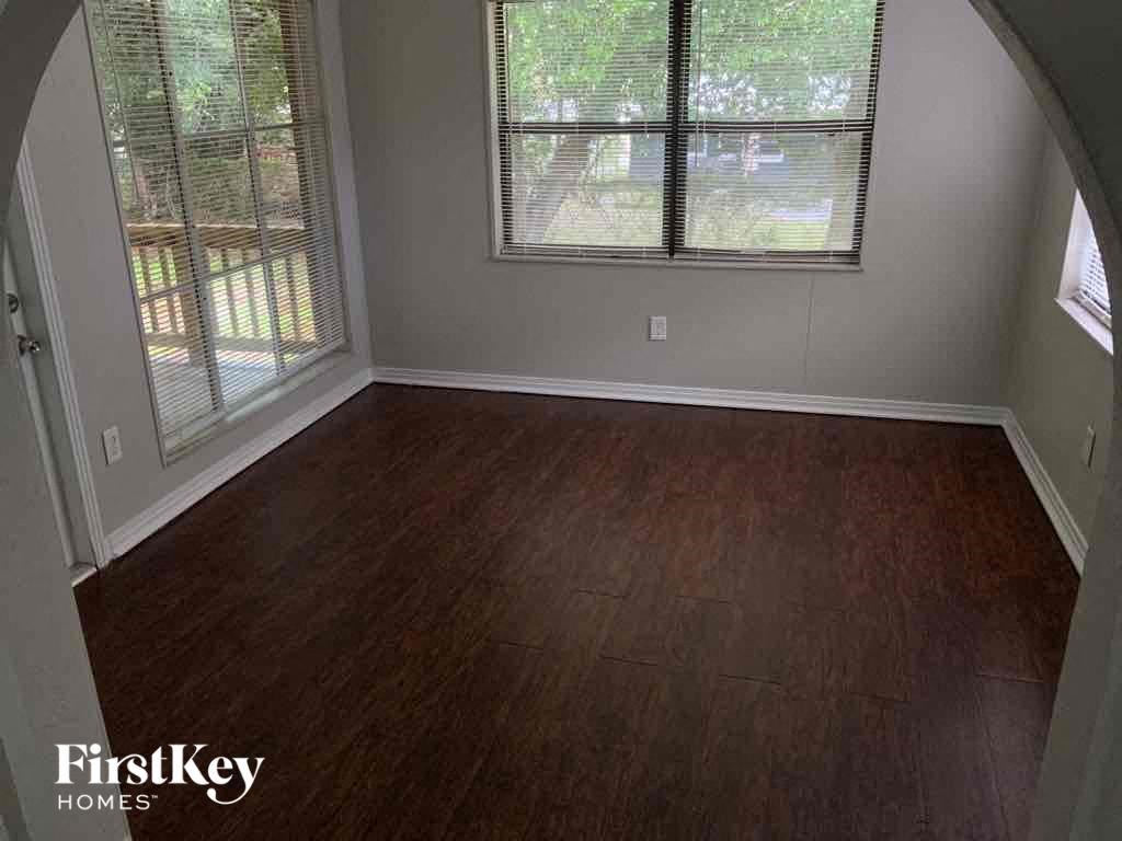 an empty living room with wooden floors and two windows
