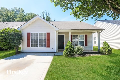 A white house with red shutters and a grey roof.