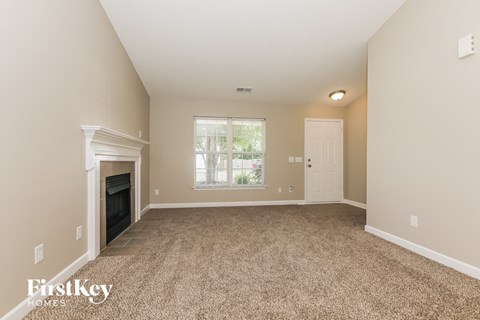A spacious room with a fireplace and carpeted floor.