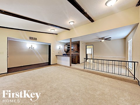 A spacious living room with a balcony and a ceiling fan.