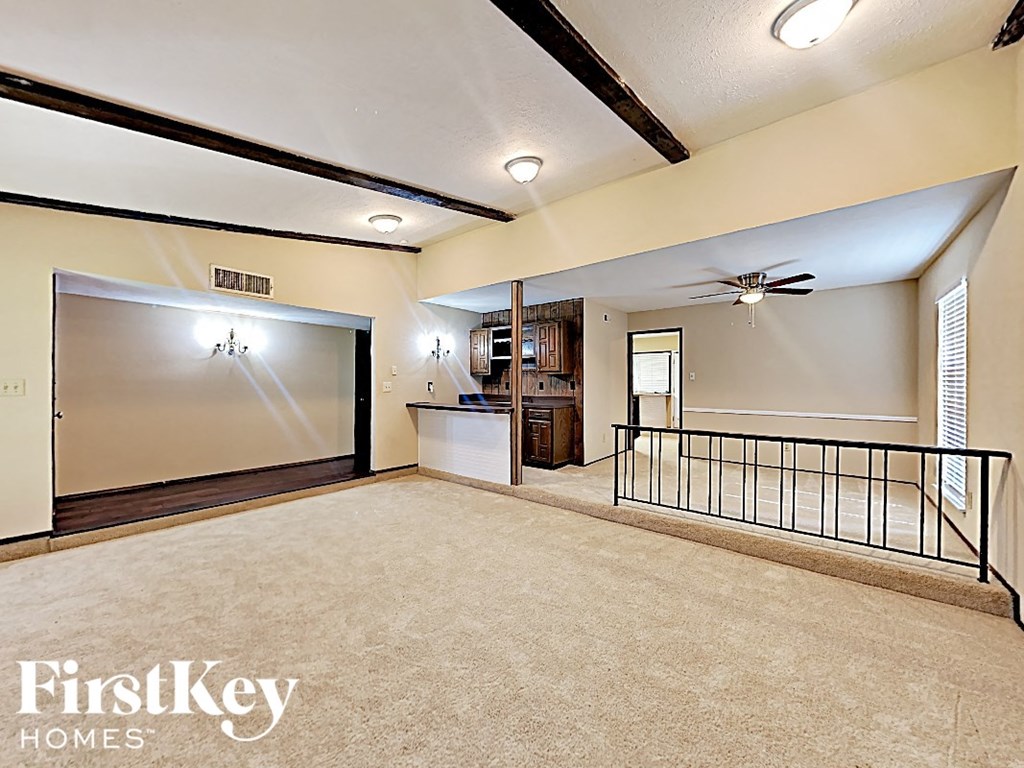 A spacious living room with a balcony and a ceiling fan.