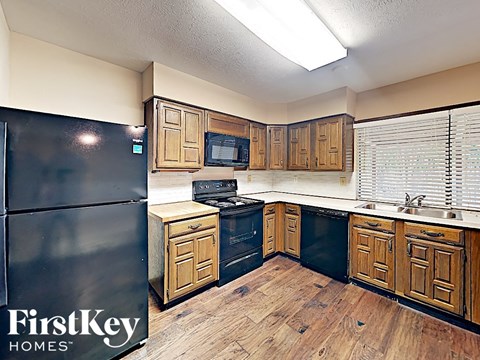 A kitchen with wooden cabinets and a black fridge.