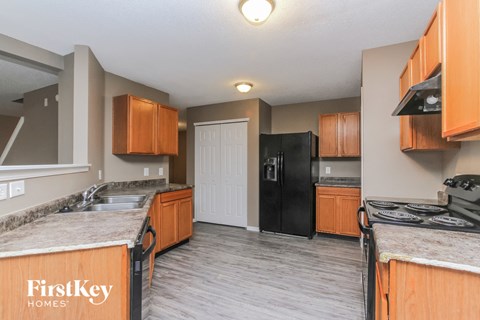 A kitchen with a black refrigerator and wooden cabinets.