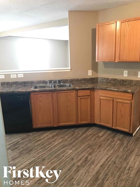 A kitchen with wooden cabinets and a black dishwasher.