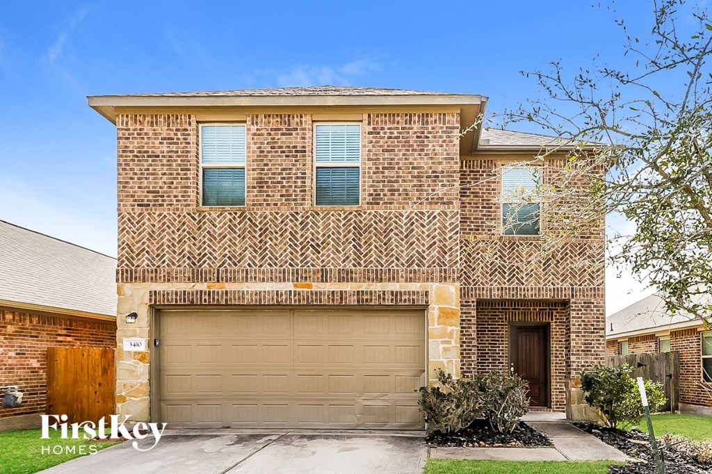A brick house with a garage door and a sign that says Firstkey Homes.