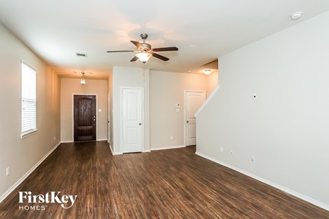 A spacious room with wooden floors and a ceiling fan.