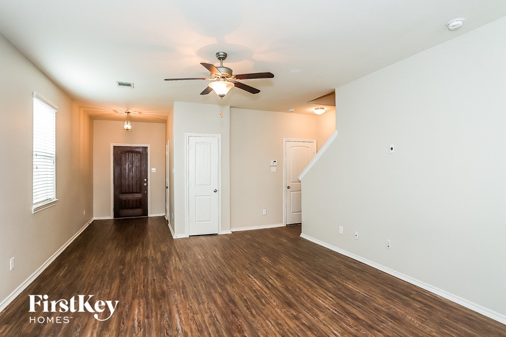 A spacious room with wooden floors and a ceiling fan.