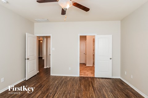 A room with a ceiling fan and wooden floors.