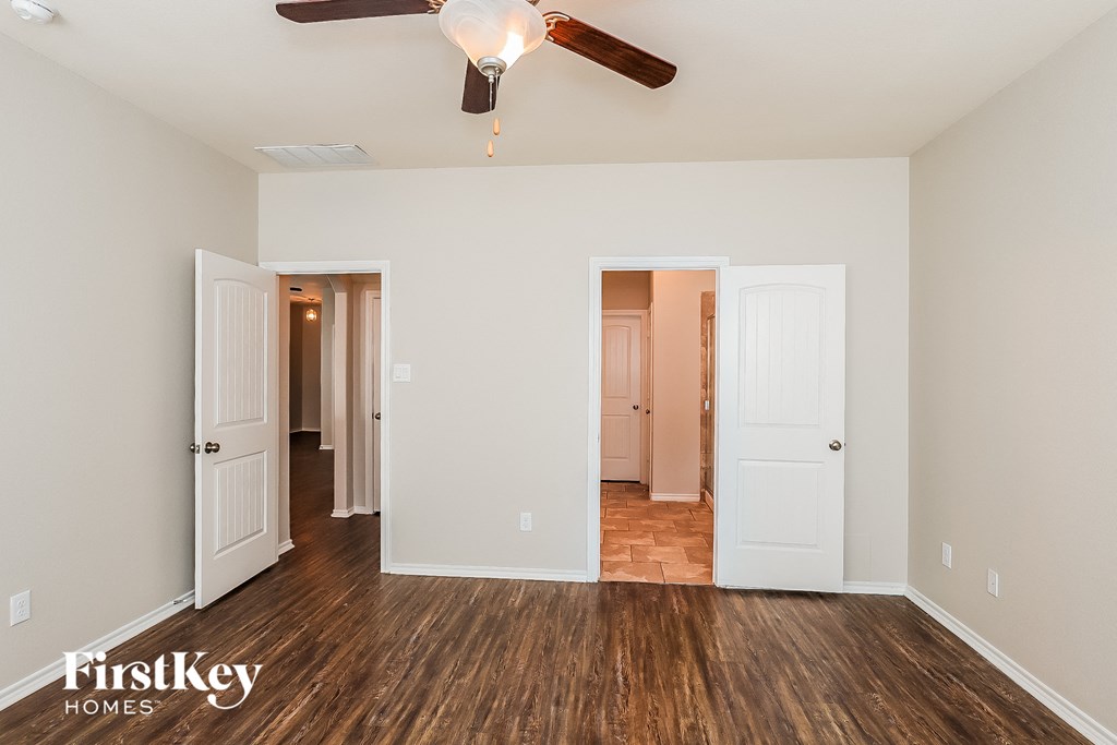 A room with a ceiling fan and wooden floors.