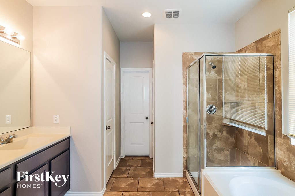 A bathroom with a walk-in shower and a white door.