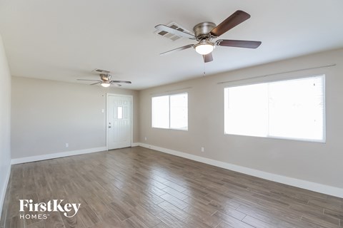 A spacious room with a ceiling fan and two windows.