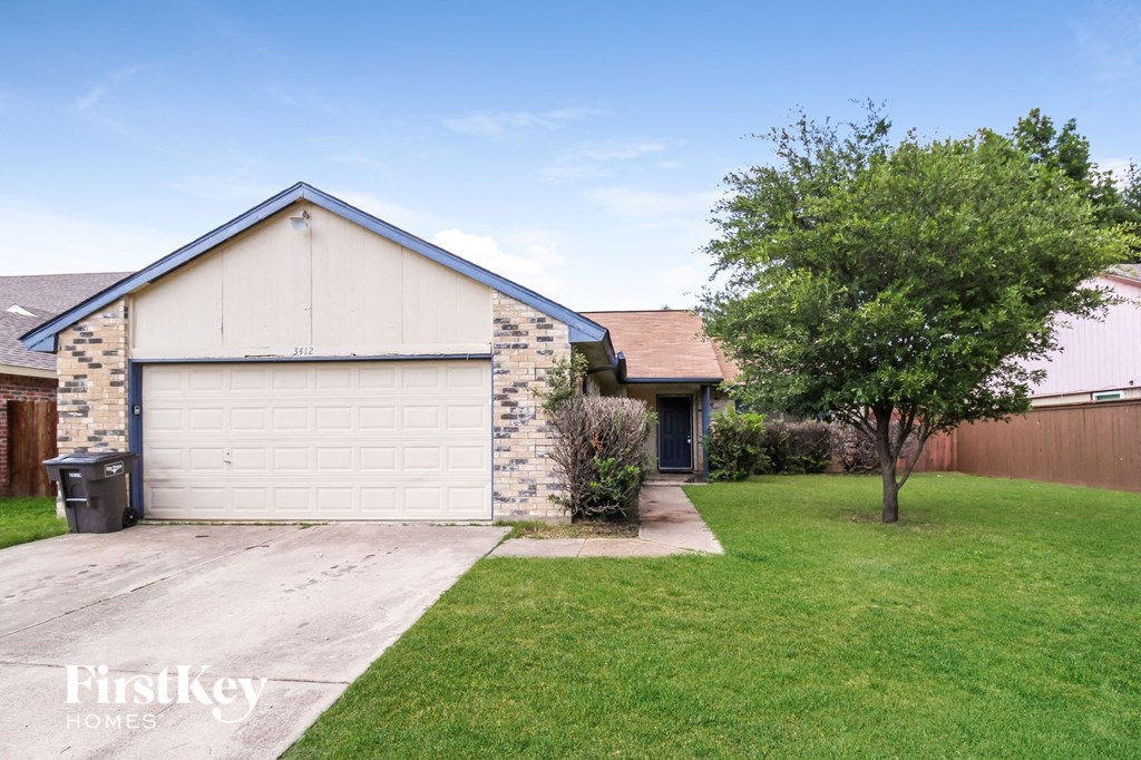 a white and brick house with a yard and a tree