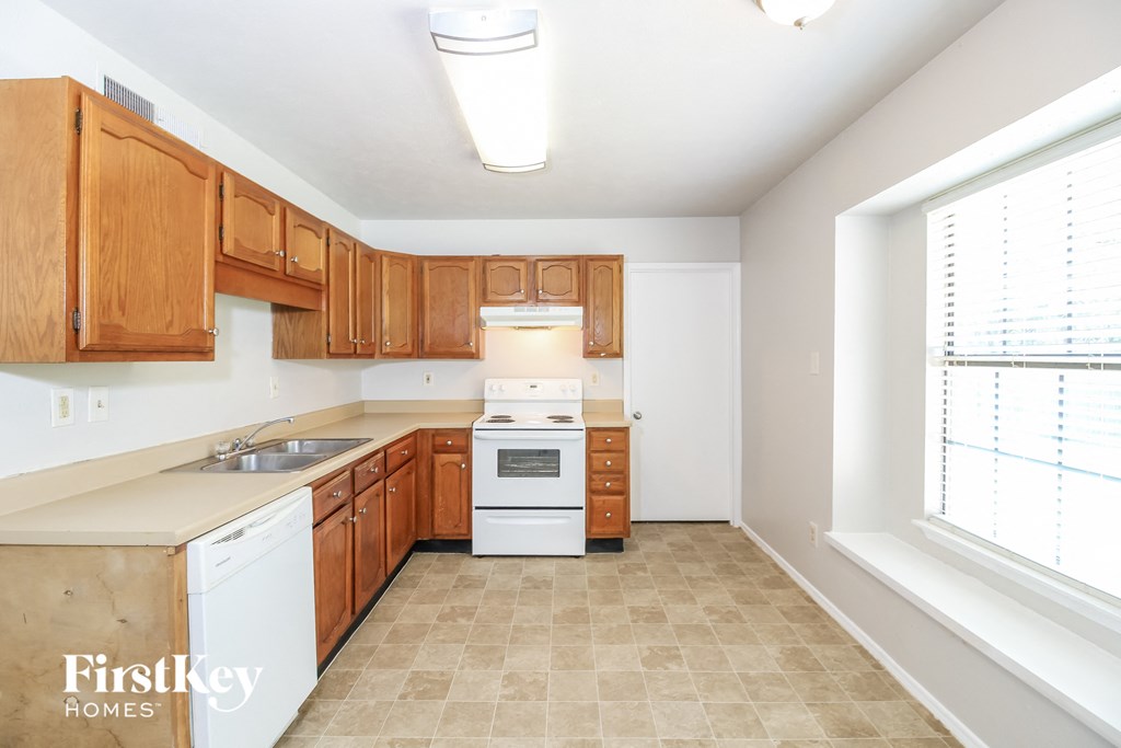 a kitchen with wood cabinets and white appliances and a window