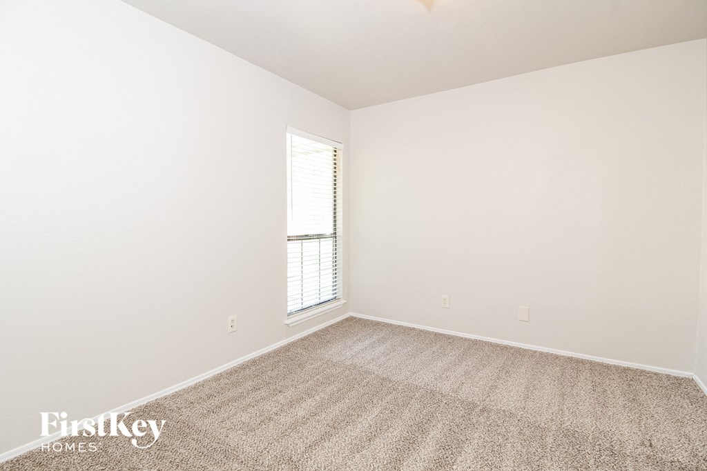 a bedroom with white walls and carpet and a window