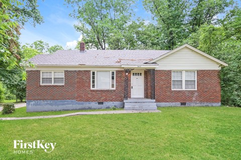 a small brick house with a white front door and a lawn