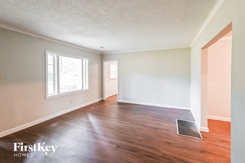 an empty living room with wood floors and white walls