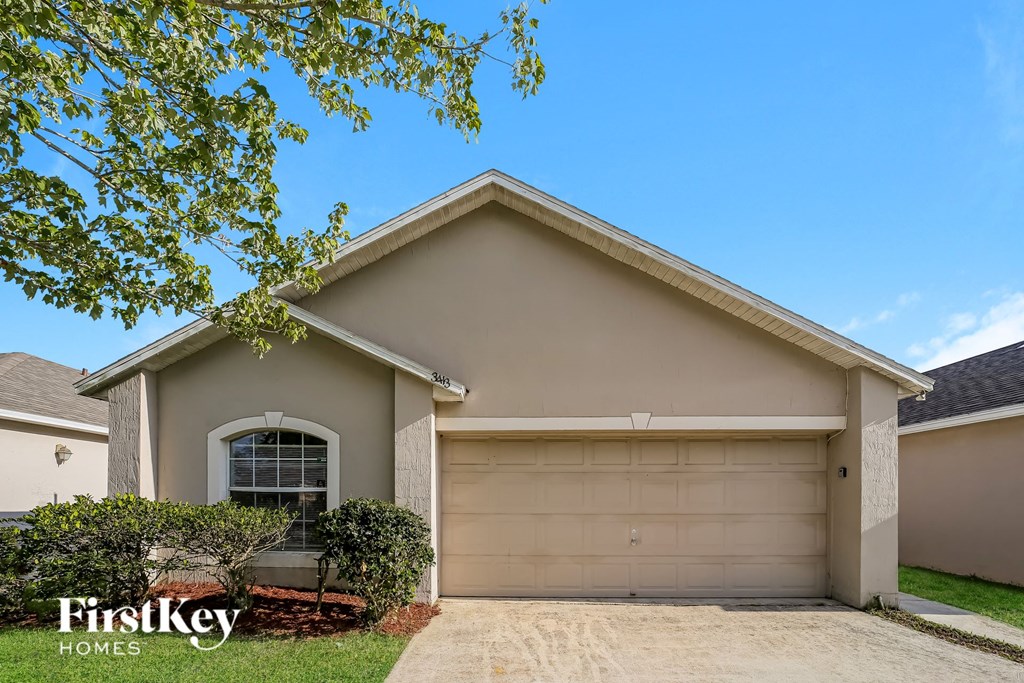 a beige house with a garage door and a tree