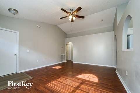 the living room and dining room with hardwood floors and a ceiling fan