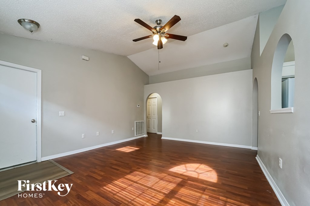the living room and dining room with hardwood floors and a ceiling fan