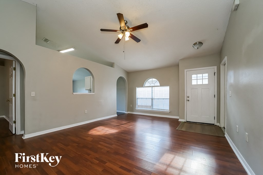 an empty living room with hardwood floors and a ceiling fan