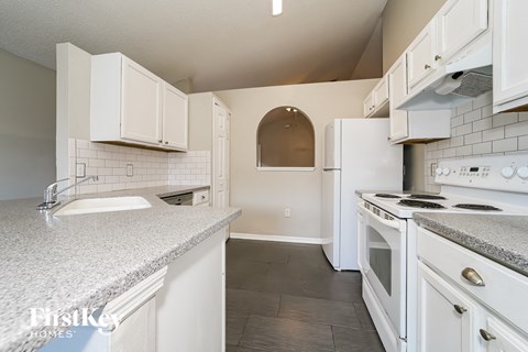 a white kitchen with white appliances and granite counter tops