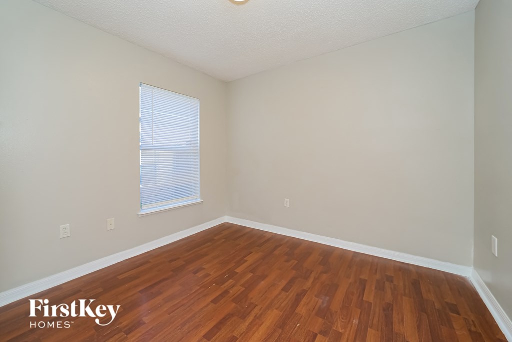 a bedroom with wood flooring and a window