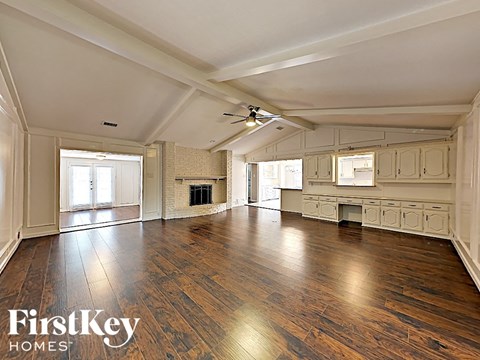 A spacious room with wooden floors and a fireplace.
