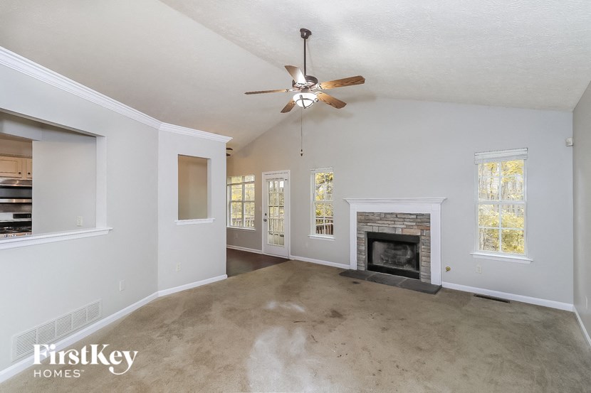 an empty living room with a fireplace and a ceiling fan