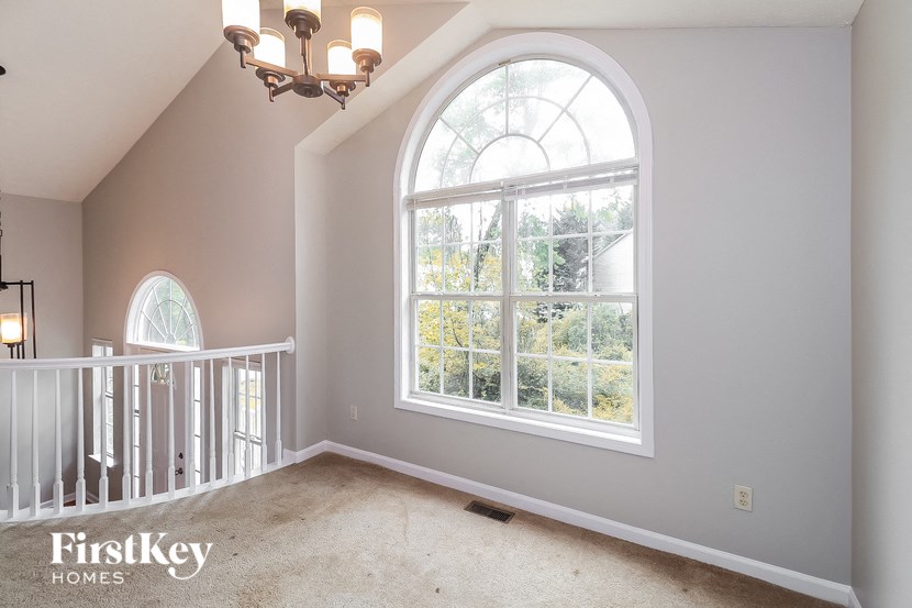 an empty bedroom with a large window and a carpeted staircase