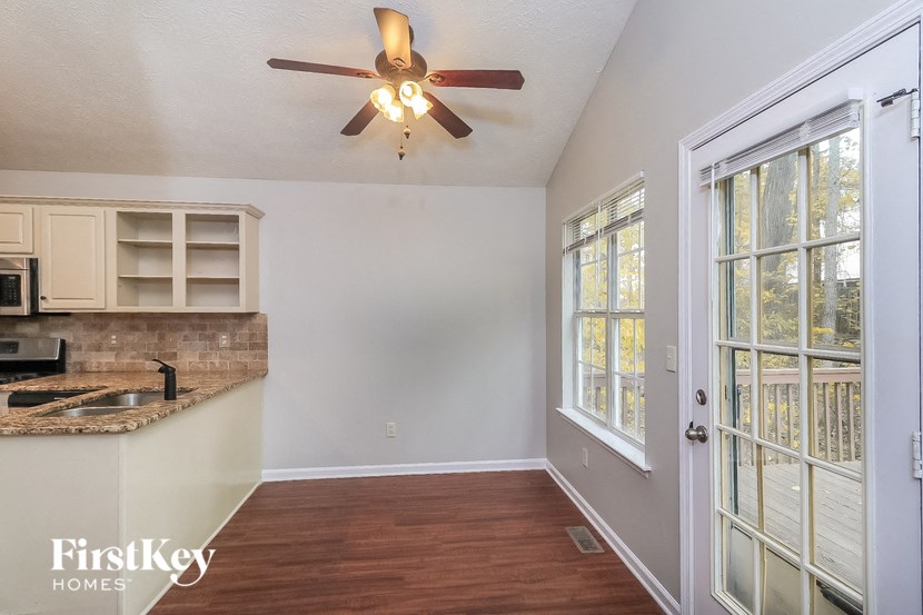 an empty living room with a kitchen and a ceiling fan