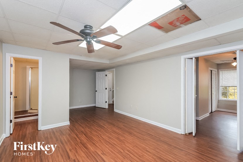 an empty living room with a ceiling fan and wood floors