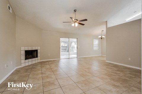 the living room has a fireplace and tile flooring and a ceiling fan