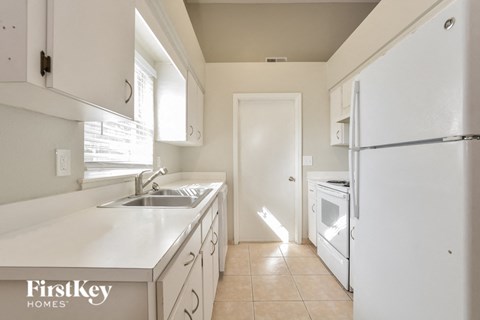 a kitchen with white cabinets and a sink and a refrigerator