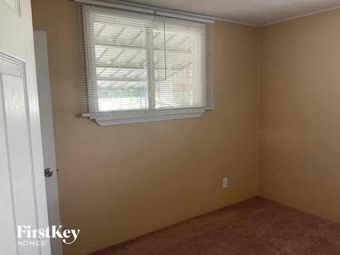 a small room with a window and a brown carpet