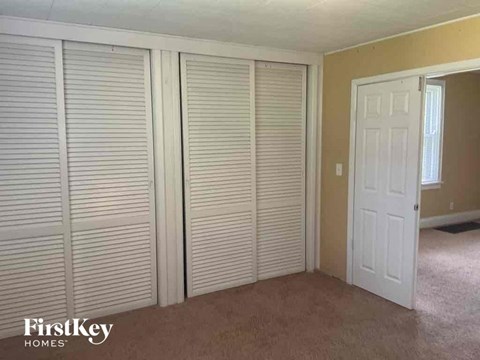 an empty bedroom with three closet doors and a door to the bathroom