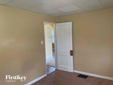 an empty living room with a door open to a hallway