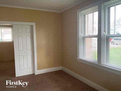 an empty room with a white door and two windows