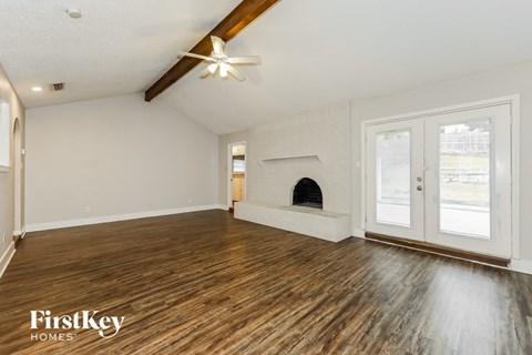 A spacious room with wooden floors and a fireplace.