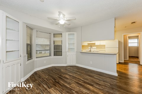 A spacious kitchen with wooden floors and white cabinets.