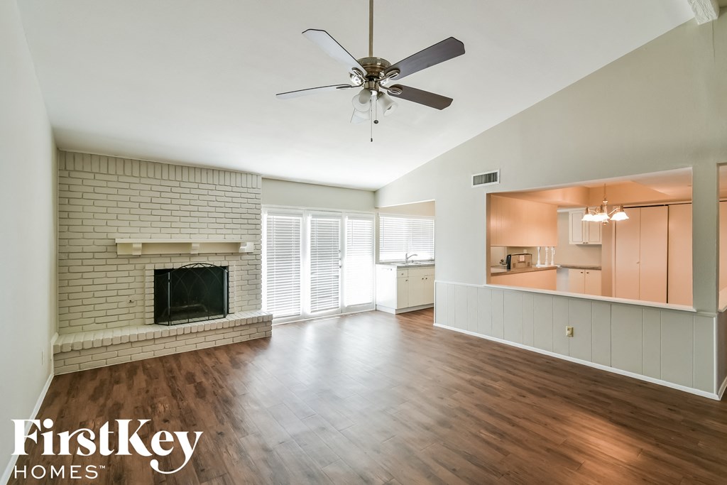 an empty living room with a fireplace and a ceiling fan