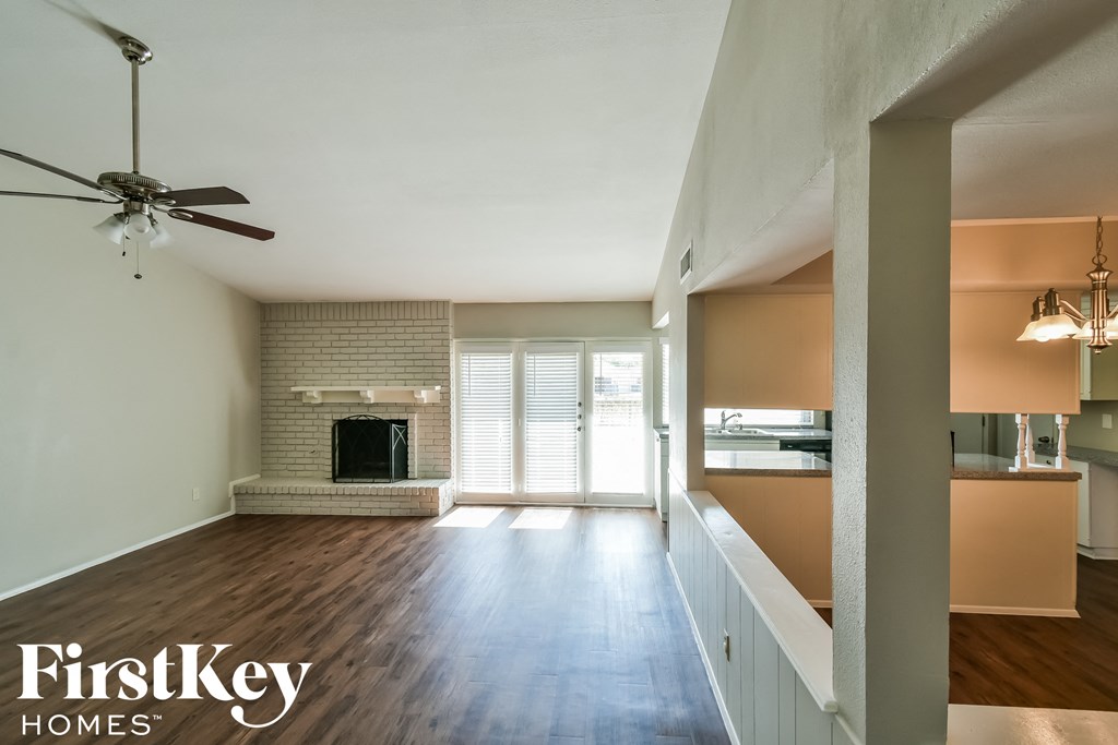 an empty living room with a ceiling fan and a fireplace
