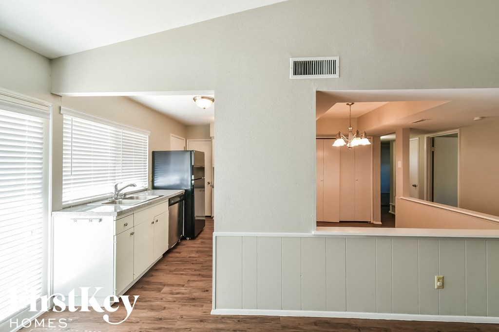a kitchen and living room with white cabinets and a window