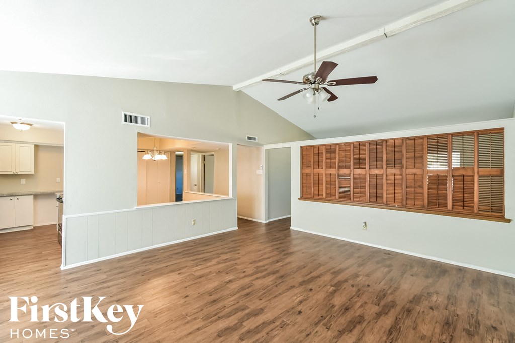 an empty living room with wood floors and a ceiling fan