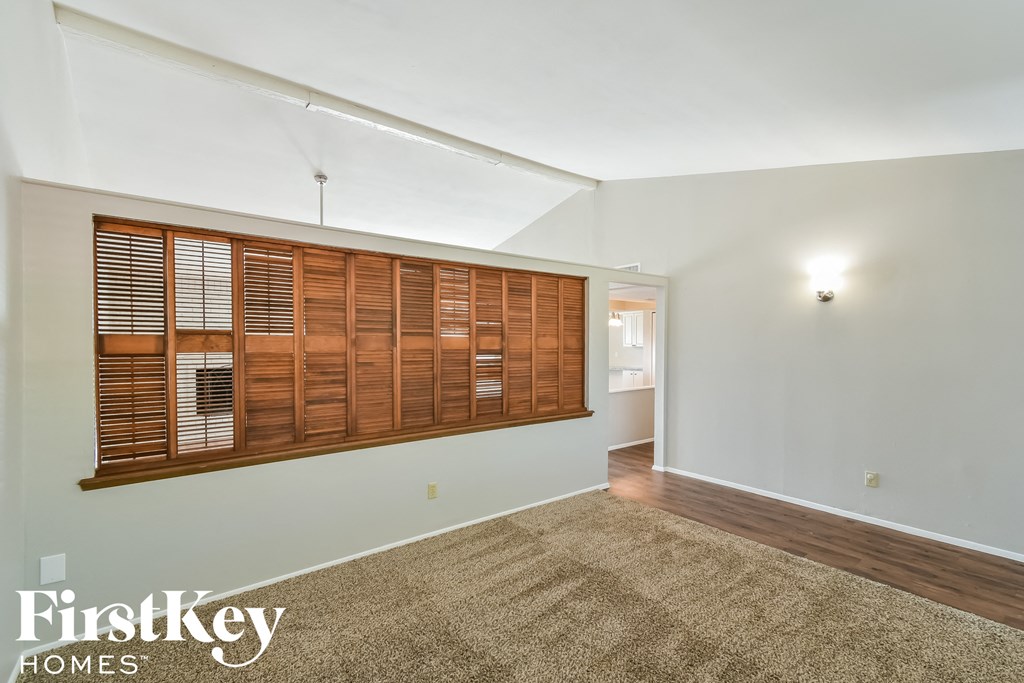 the living room has a large window with wooden shutters