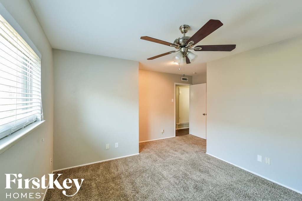 an empty room with a ceiling fan and a window