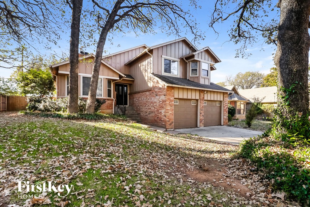 the front of a house with a garage and trees