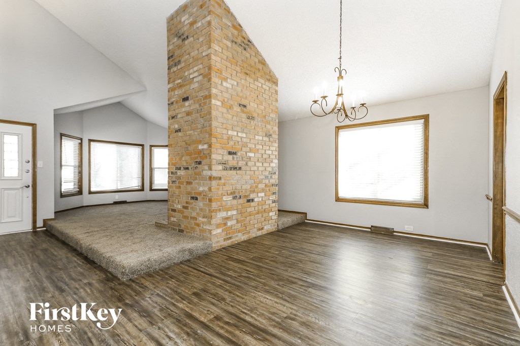 an empty living room with a brick fireplace and wood floors