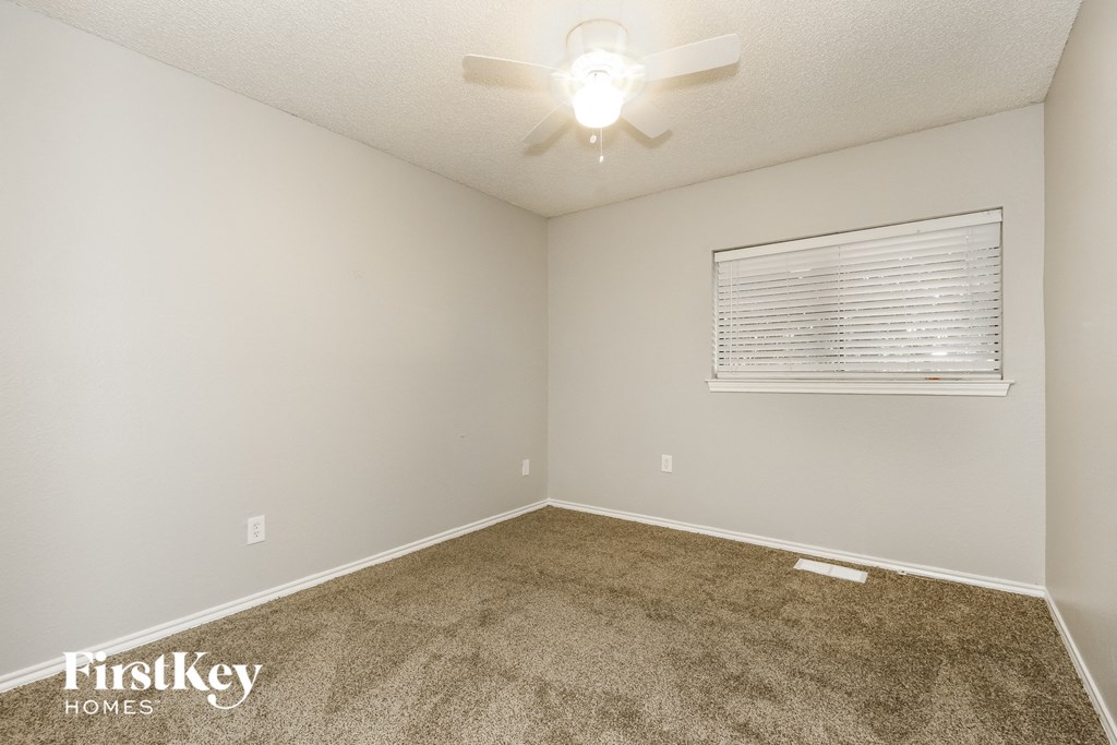 the spacious living room with carpeting and a ceiling fan