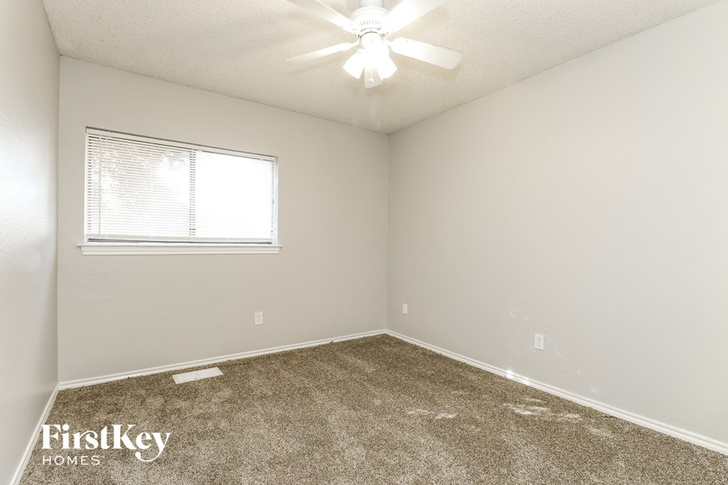 the spacious bedroom of this manufactured home has a carpeted floor and a window